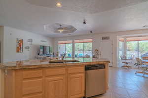 Kitchen featuring stainless steel dishwasher, a healthy amount of sunlight, sink, and ceiling fan