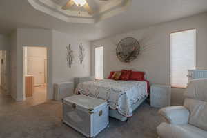 Tiled bedroom featuring a tray ceiling, ceiling fan, and radiator