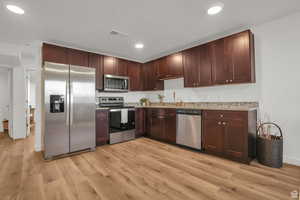 Kitchen featuring appliances with stainless steel finishes, light hardwood / wood-style flooring, sink, and dark brown cabinetry