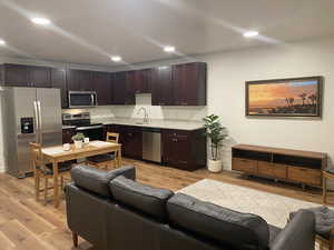 Kitchen with appliances with stainless steel finishes, sink, and light hardwood / wood-style floors