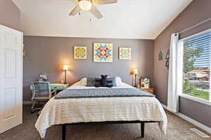 Bedroom with lofted ceiling, ceiling fan, and carpet