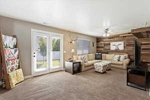 Living room with ceiling fan, wooden walls, and carpet floors