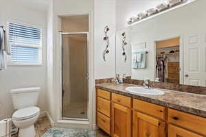 Bathroom with tile patterned flooring, vanity, toilet, and a shower with door