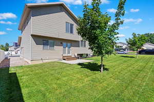 Rear view of property with a lawn and a patio