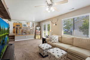 Carpeted living room featuring ceiling fan