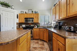 Kitchen featuring tile patterned flooring, backsplash, sink, and appliances with stainless steel finishes