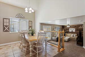 Dining room with ceiling fan with notable chandelier and light tile patterned flooring