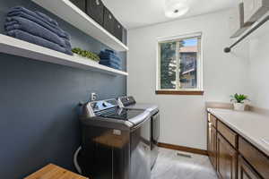 Washroom featuring cabinets, separate washer and dryer, and light hardwood / wood-style floors