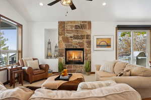 Living room with light colored carpet, ceiling fan, lofted ceiling, and a fireplace