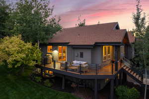 Back house at dusk featuring outdoor lounge area and a deck