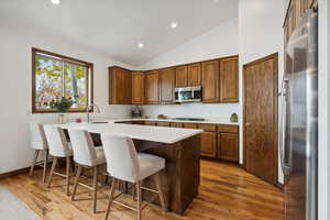 Kitchen with appliances with stainless steel finishes, sink, kitchen peninsula, vaulted ceiling, and a breakfast bar area