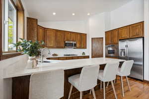 Kitchen with appliances with stainless steel finishes, sink, a center island, a breakfast bar area, and light hardwood / wood-style flooring