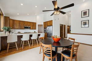 Dining space with high vaulted ceiling, sink, light wood-type flooring, and ceiling fan