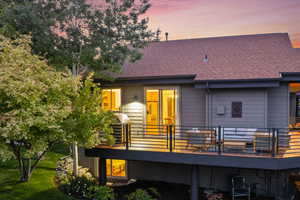 Back house at dusk featuring a wooden deck