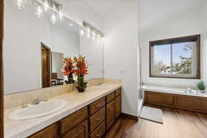 Bathroom with vanity, lofted ceiling, hardwood / wood-style floors, and separate shower and tub