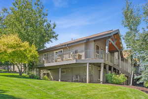 Rear view of property featuring a yard and a wooden deck