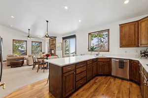 Kitchen with sink, a fireplace, light hardwood / wood-style floors, lofted ceiling, and stainless steel dishwasher