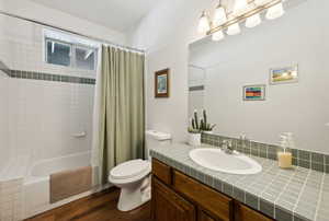 Full bathroom with vanity, toilet, hardwood / wood-style flooring, and shower / bath combo with shower curtain