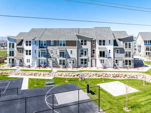 Rear view of property featuring basketball hoop and a lawn