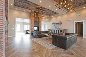 Living room with a brick fireplace, a towering ceiling, and parquet flooring