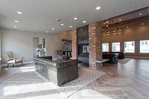 Living room with light parquet floors, a brick fireplace, and a textured ceiling