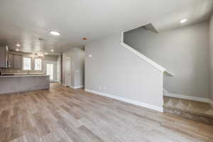 Unfurnished living room with an inviting chandelier and light hardwood / wood-style floors