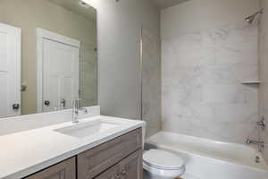 Full bathroom with tiled shower / bath, vanity, and toilet