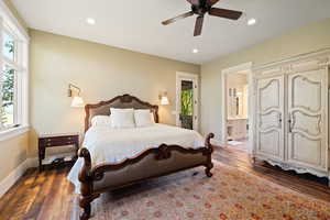 Bedroom with ensuite bath, dark hardwood / wood-style flooring, and ceiling fan