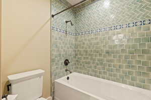 Bathroom featuring tiled shower / bath and toilet