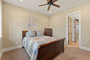 Carpeted bedroom with ceiling fan and ensuite bath