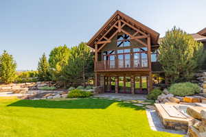 Rear view of property featuring a patio, a lawn, and a wooden deck