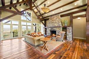 Living room with a wealth of natural light, hardwood / wood-style flooring, a fireplace, and beamed ceiling