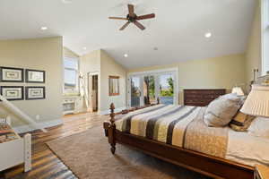 Bedroom with ensuite bath, french doors, lofted ceiling, wood-type flooring, and ceiling fan