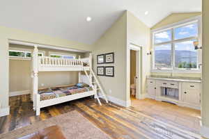 Bedroom featuring ensuite bath, hardwood / wood-style floors, lofted ceiling, and a mountain view