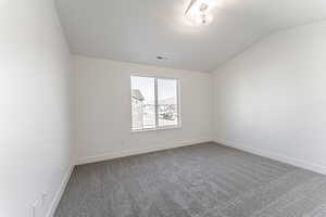 Carpeted empty room with lofted ceiling