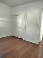 Unfurnished bedroom featuring dark wood-type flooring and a closet