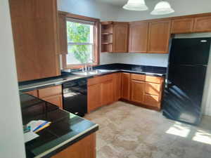 Kitchen with black appliances, light tile patterned floors, and sink