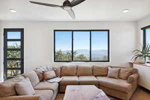 Living room featuring a healthy amount of sunlight, ceiling fan, a mountain view, and hardwood / wood-style flooring