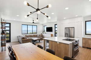 Kitchen with white cabinets, a center island, light hardwood / wood-style flooring, stainless steel appliances, and ceiling fan