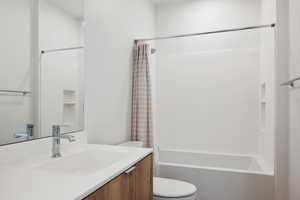 Full bathroom with toilet, shower / tub combo with curtain, and vanity