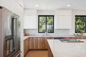 Kitchen featuring light stone counters, stainless steel appliances, light hardwood / wood-style floors, and white cabinetry