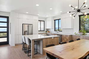 Kitchen with a wealth of natural light, a center island, stainless steel appliances, and white cabinetry