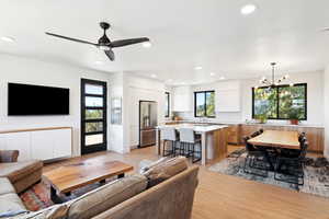 Living room featuring sink, ceiling fan with notable chandelier, and light hardwood / wood-style floors