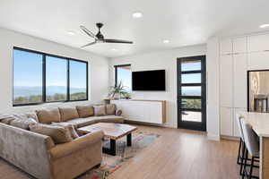 Living room featuring light wood-type flooring, ceiling fan, and a mountain view