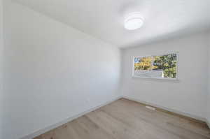 Unfurnished room featuring light wood-type flooring and a textured ceiling