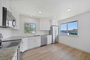 Kitchen featuring stainless steel appliances, sink, and white cabinetry