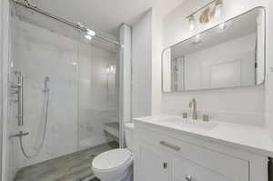 Bathroom featuring an enclosed shower, toilet, and vanity