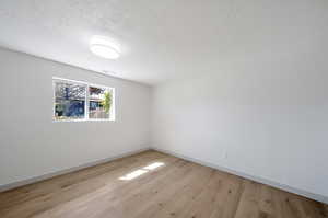 Empty room featuring a textured ceiling and light wood-type flooring