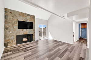 Living room with a fireplace, light hardwood / wood-style vinyl flooring, and lofted ceiling