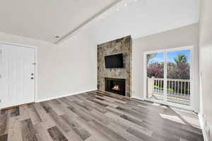 Living room featuring a fireplace, vaulted ceiling, and light wood-type flooring